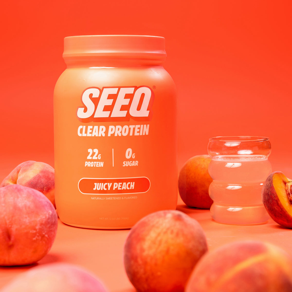 A jar of SEEQ Clear Protein in Juicy Peach flavor, styled with fresh peaches and a glass of peach-colored liquid on a solid orange background.