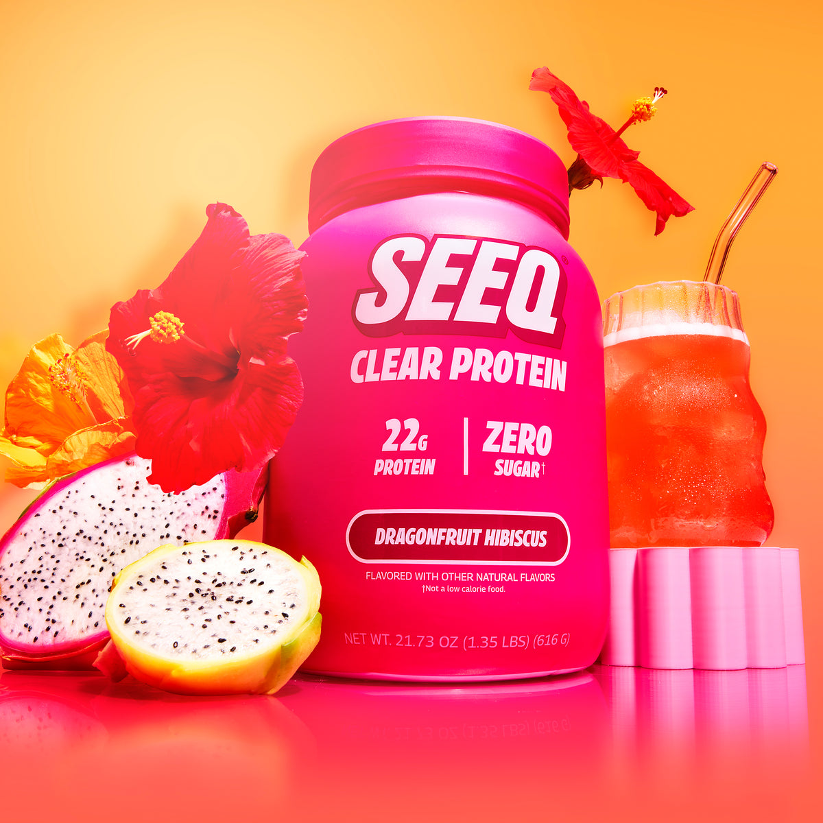 A bright pink tub of SEEQ Clear Protein powder stands on a pink surface against a warm orange-yellow gradient background. The label reads '22g Protein | Zero Sugar' and 'Dragonfruit Hibiscus.