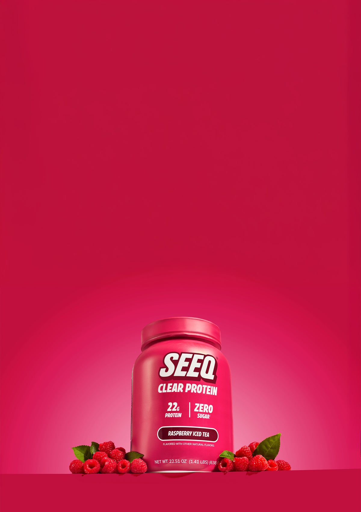 A jar of SEEQ Clear Protein powder in Raspberry Ice Tea flavor, styled on a matching pink background with fresh raspberries at its base.