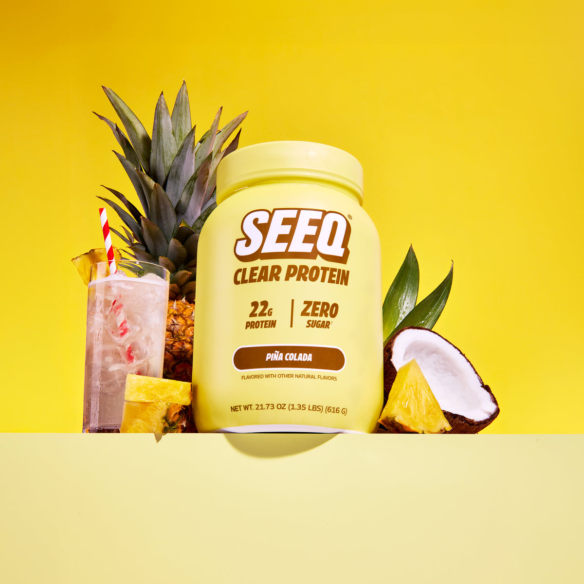 SEEQ Clear Protein container with a cocktail and pineapple on a yellow background