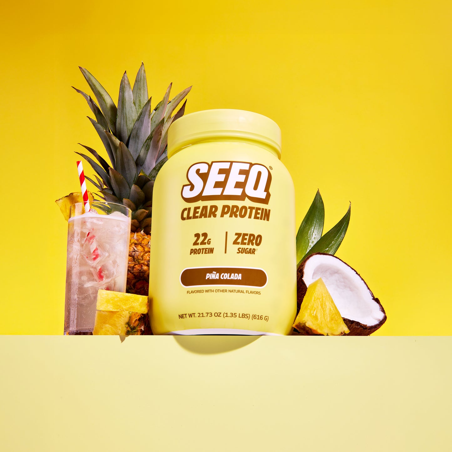 SEEQ Clear Protein container with a cocktail and pineapple on a yellow background